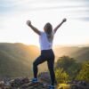 woman in white shirt and black pants standing on rocky mountain during daytime